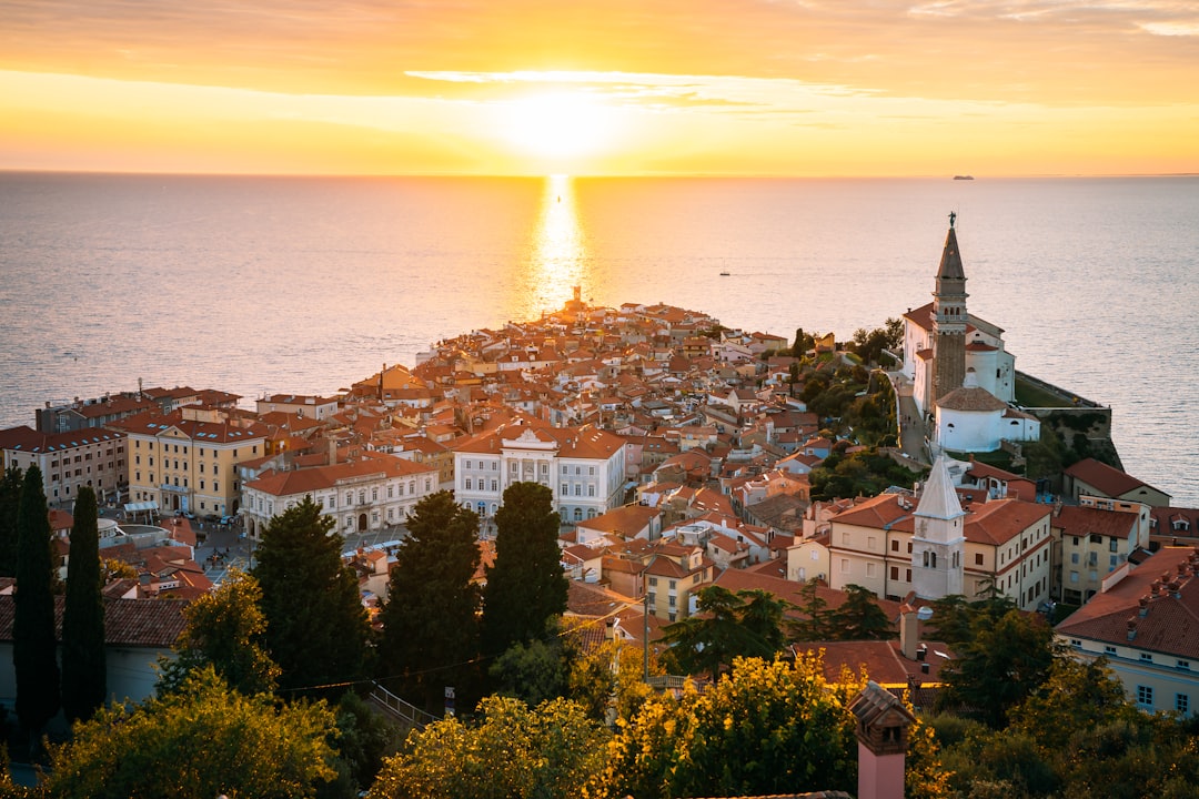 piran - the sun is setting over a city by the ocean